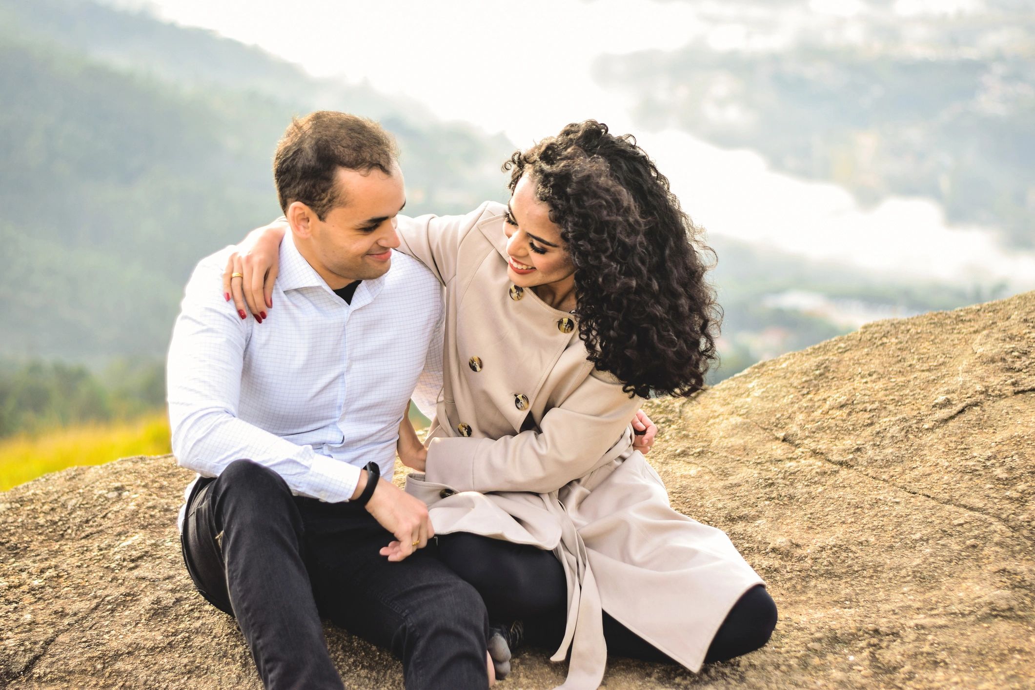 Happy young couple, sitting on a rock in a mountain