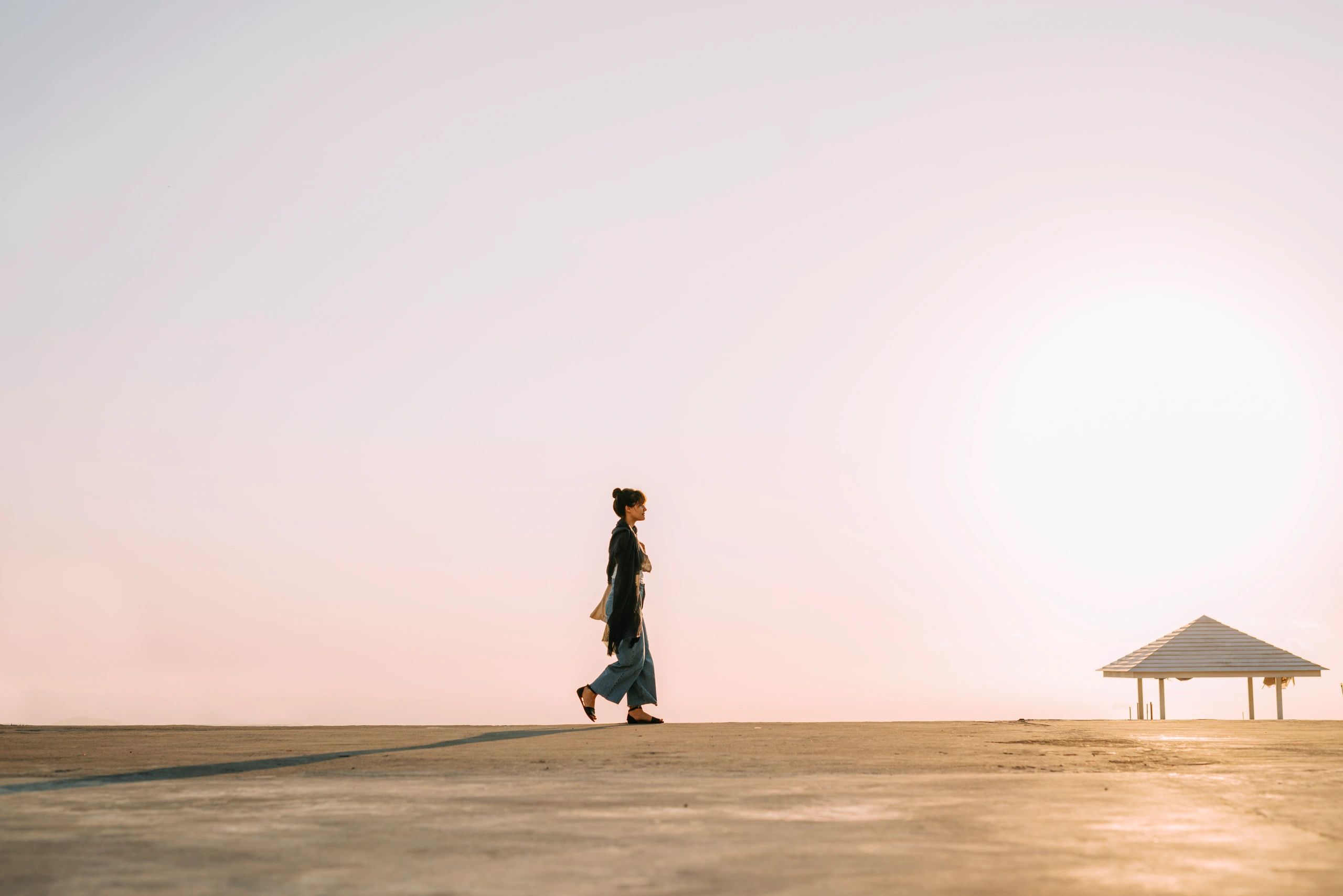 Woman walking on a sandy beach in warm sunset light