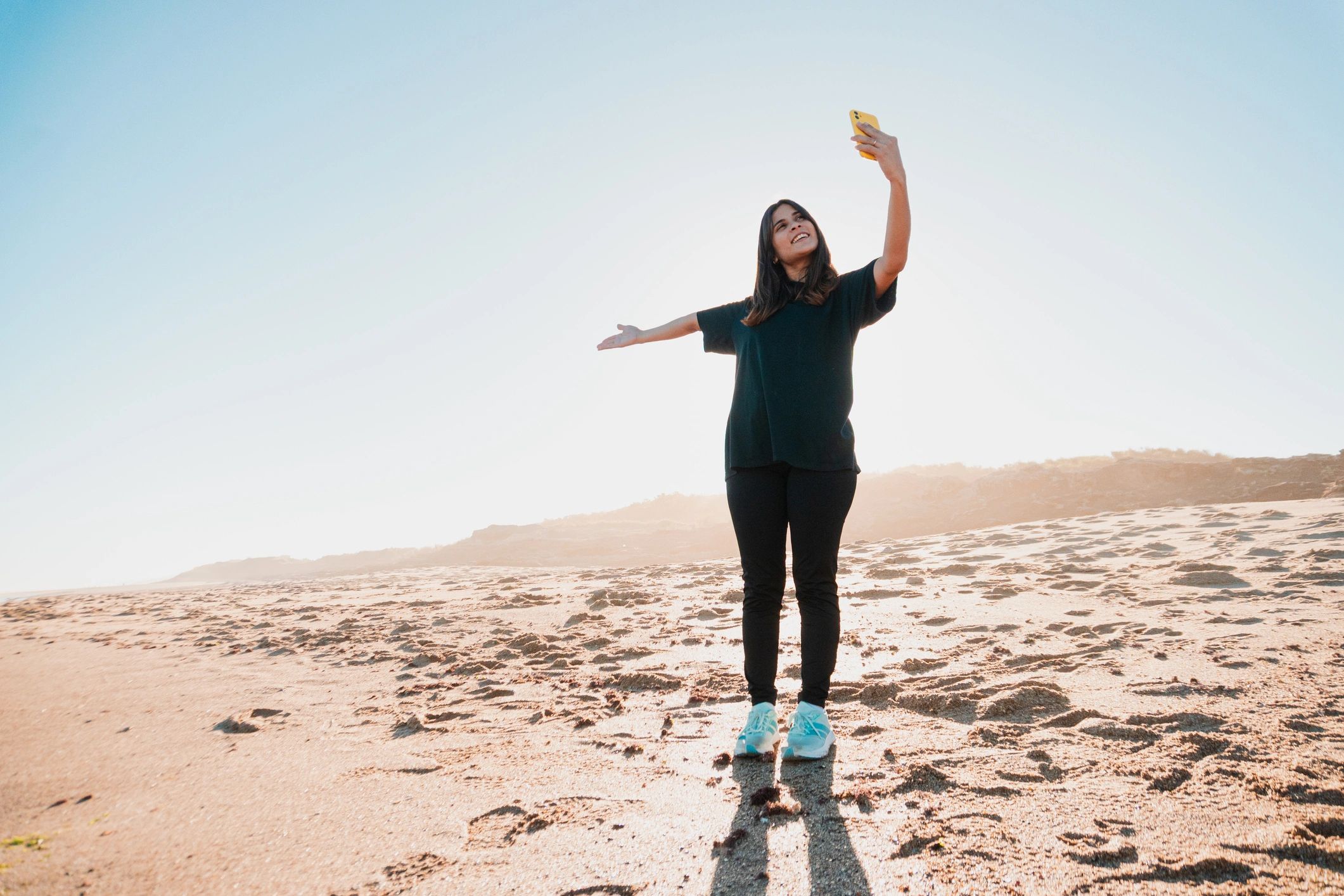 Woman taking a selfie at the beach during sunset