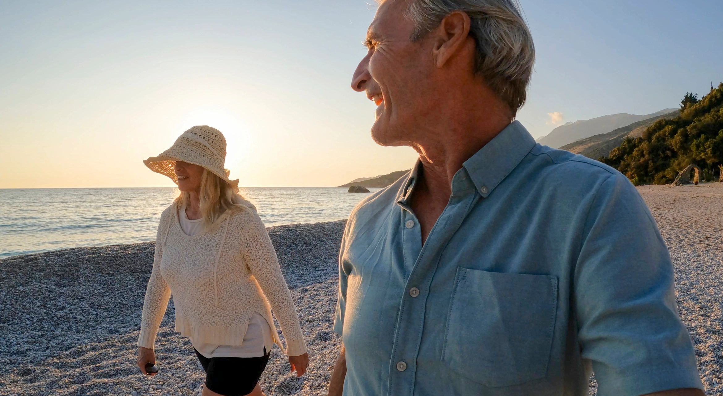 Couple walking on beach at sunrise