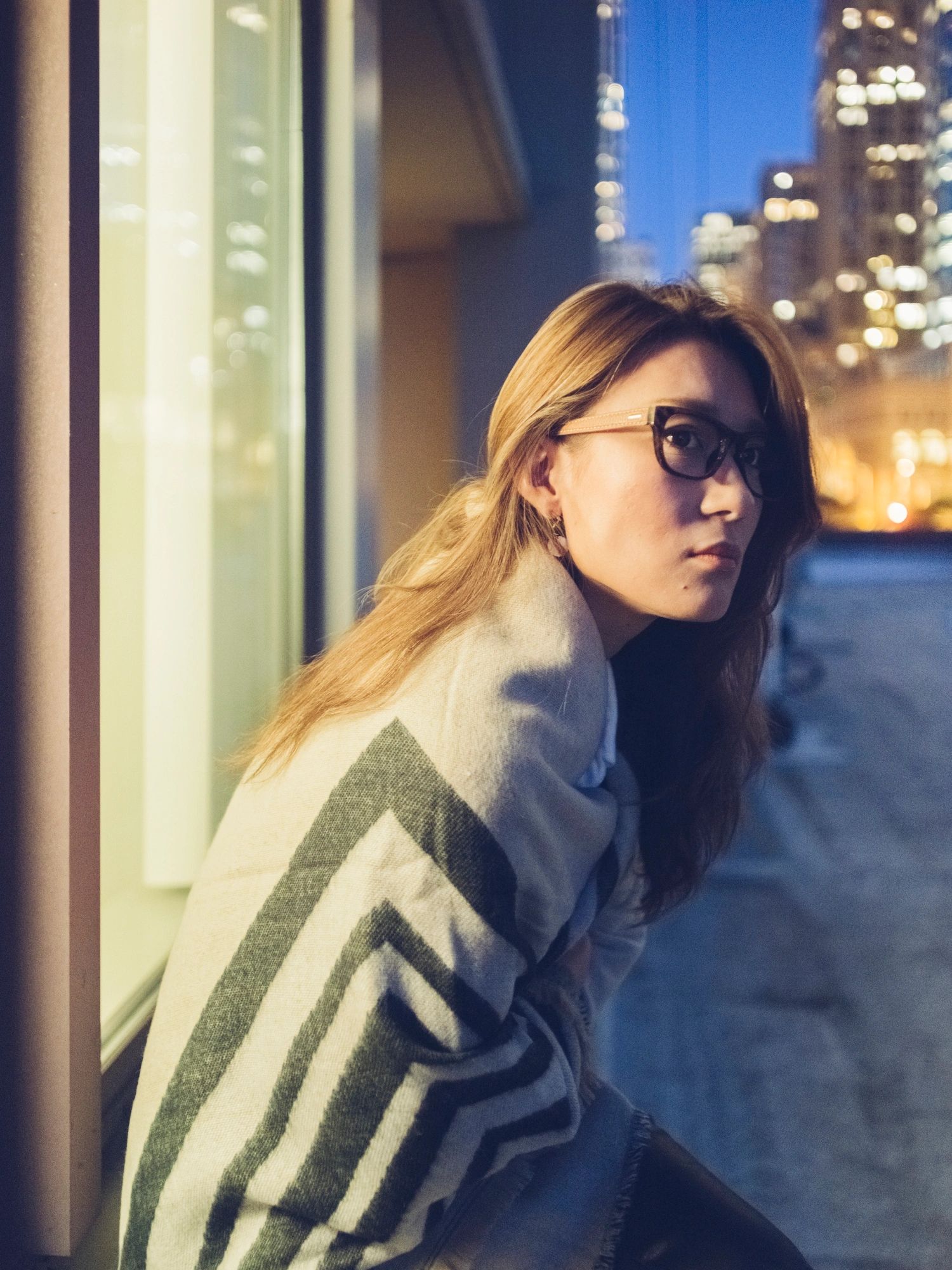 Young woman wrapped in a blanket at night
